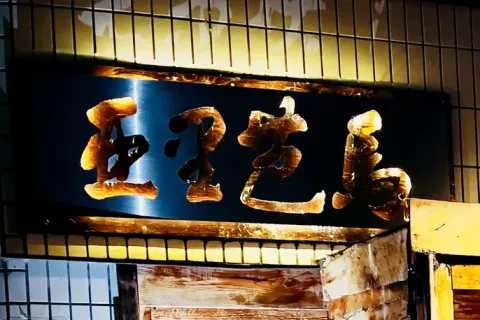 店の入口の上に掛かる「亜里芭馬」の看板。夜は灯りがともる